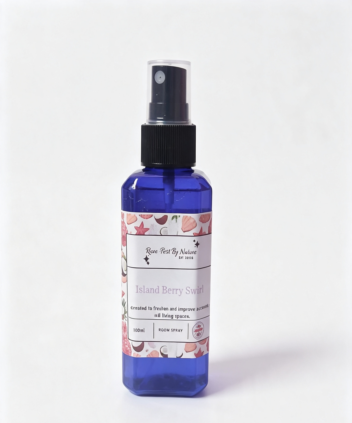 A 100ml blue mist bottle with a black spray nozzle and a white label featuring pink seashells and coconut illustrations. The label reads 'Rowe-best By Nature' and 'Island Berry Swirl'.