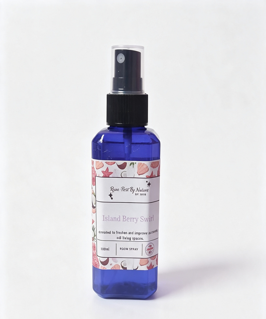 A 100ml blue mist bottle with a black spray nozzle and a white label featuring pink seashells and coconut illustrations. The label reads 'Rowe-best By Nature' and 'Island Berry Swirl'.
