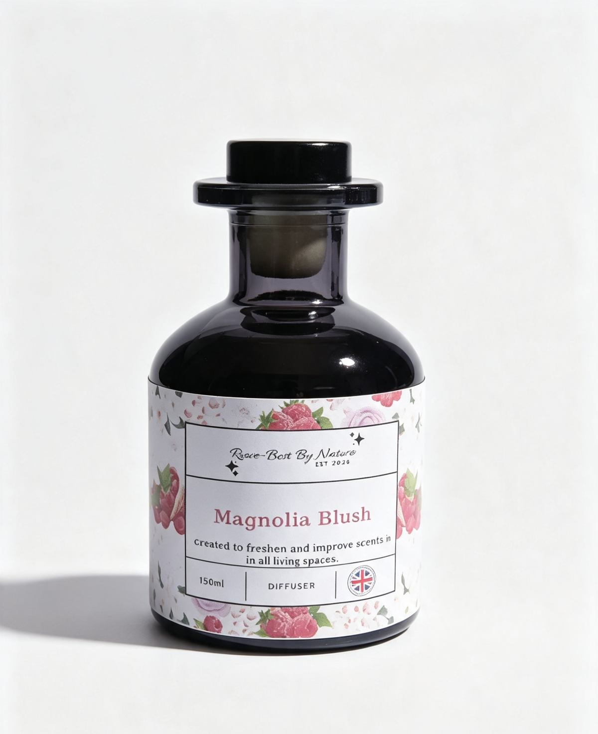 A 150ml diffuser bottle by Row-Best By Nature, featuring a black glass body, black screw cap, and a white label decorated with pink rose illustrations and the scent name 'Magnolia Blush'.